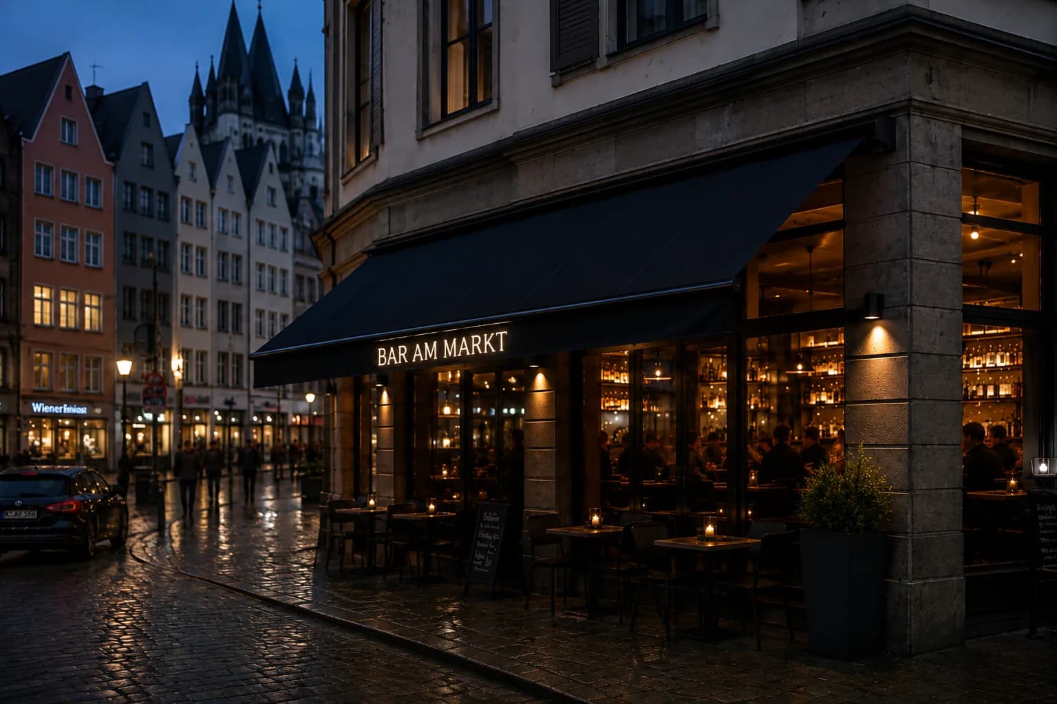 Historische Eckfassade einer Bar am Abend mit schwarzer Markise, leuchtendem Schriftzug „BAR AM MARKT“ und Tischen auf regennassem Kopfsteinpflaster.