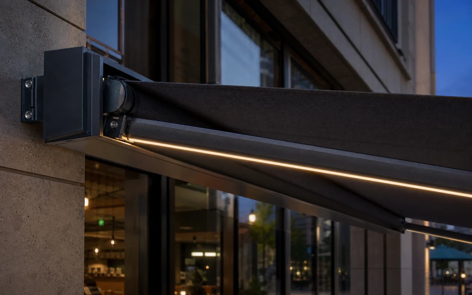 Detailansicht einer grafitfarbenen Markise mit linear beleuchteter Vorderkante über einem modernen Café-Eingang.