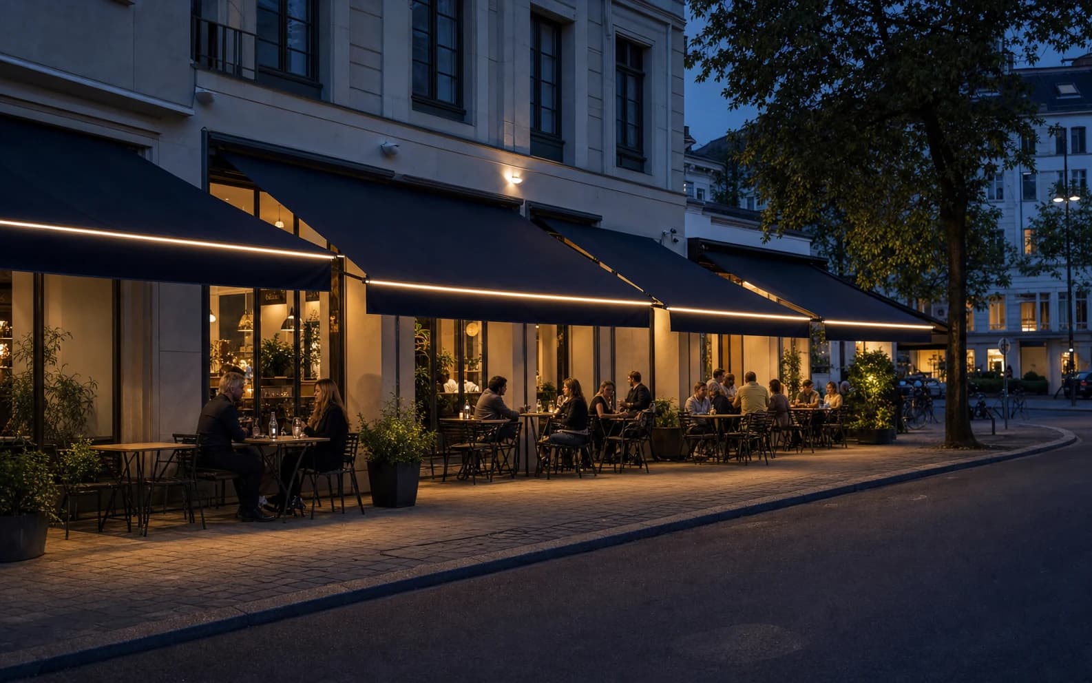 Abendliche Café-Terrasse mit mehreren dunkelblauen Markisen und warm leuchtenden Vorderkanten.
